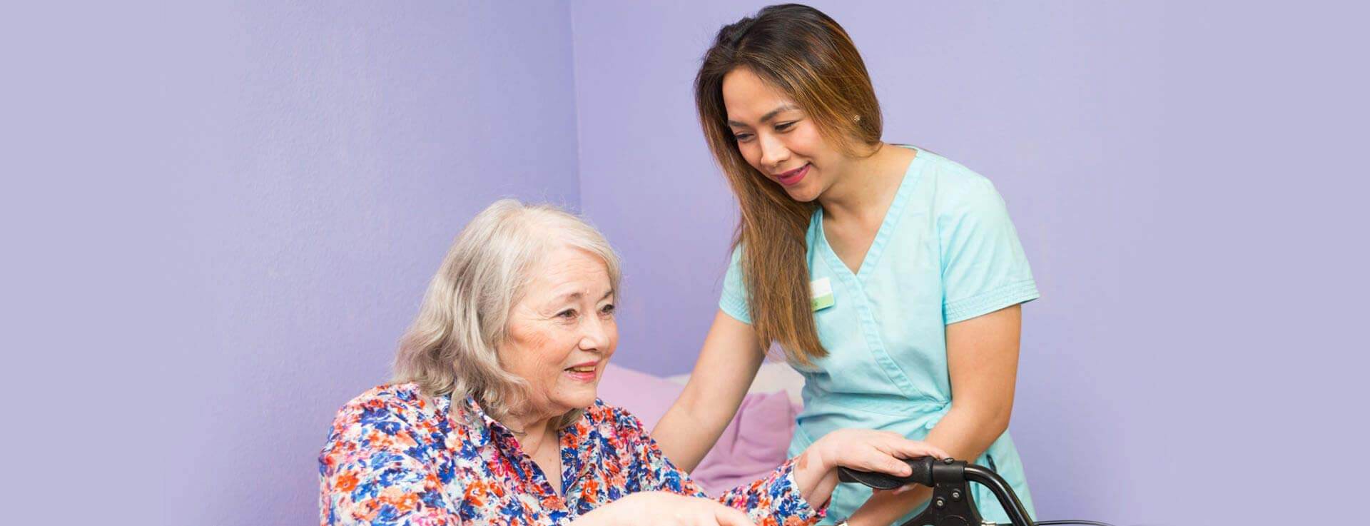 Caregiver helping elderly woman with walker