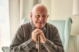 Smiling Person Wearing Sweater And Sitting With Cane In Hands