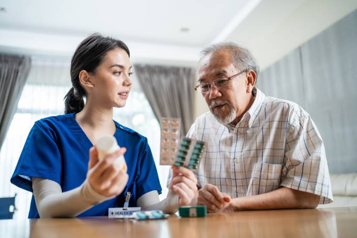 Young caregiver explaining prescriptions to an elderly man