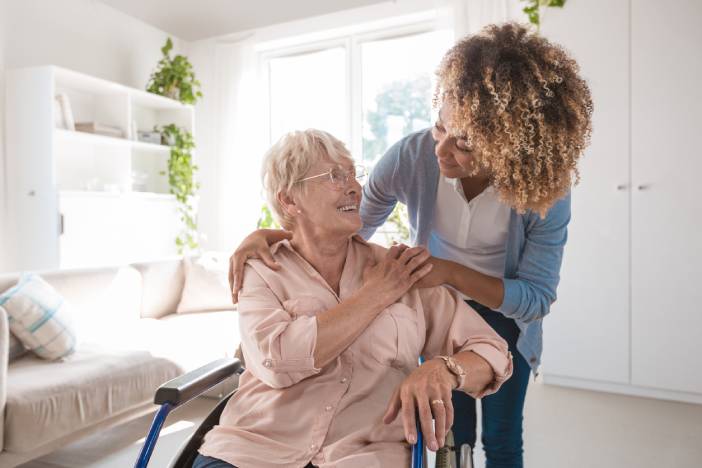 Senior woman sitting in a wheelchair while talking to a caregiver