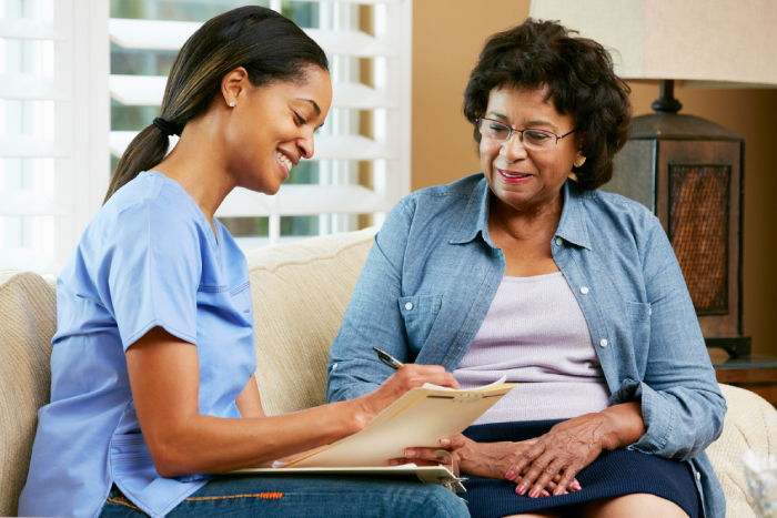 Caregiver sitting beside a senior patient while making a checklist