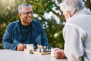 One person smiles at an opponent while playing chess outdoors